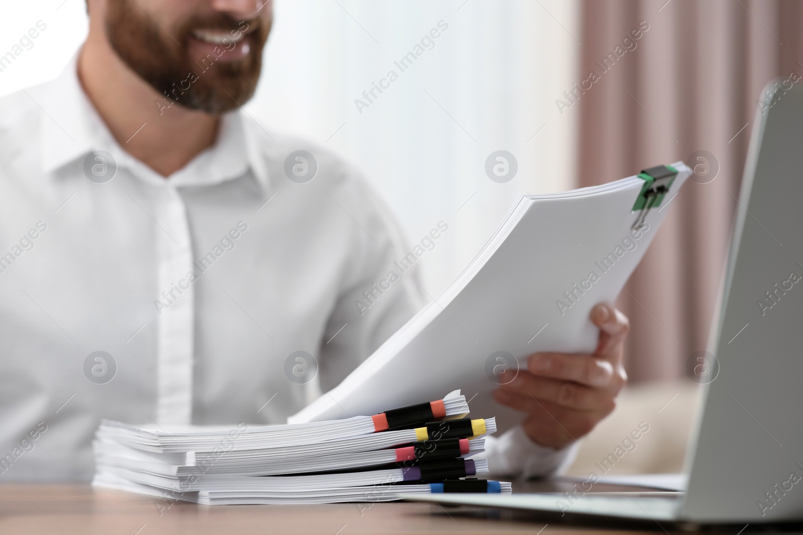 Photo of Man working with documents at wooden table in office, closeup