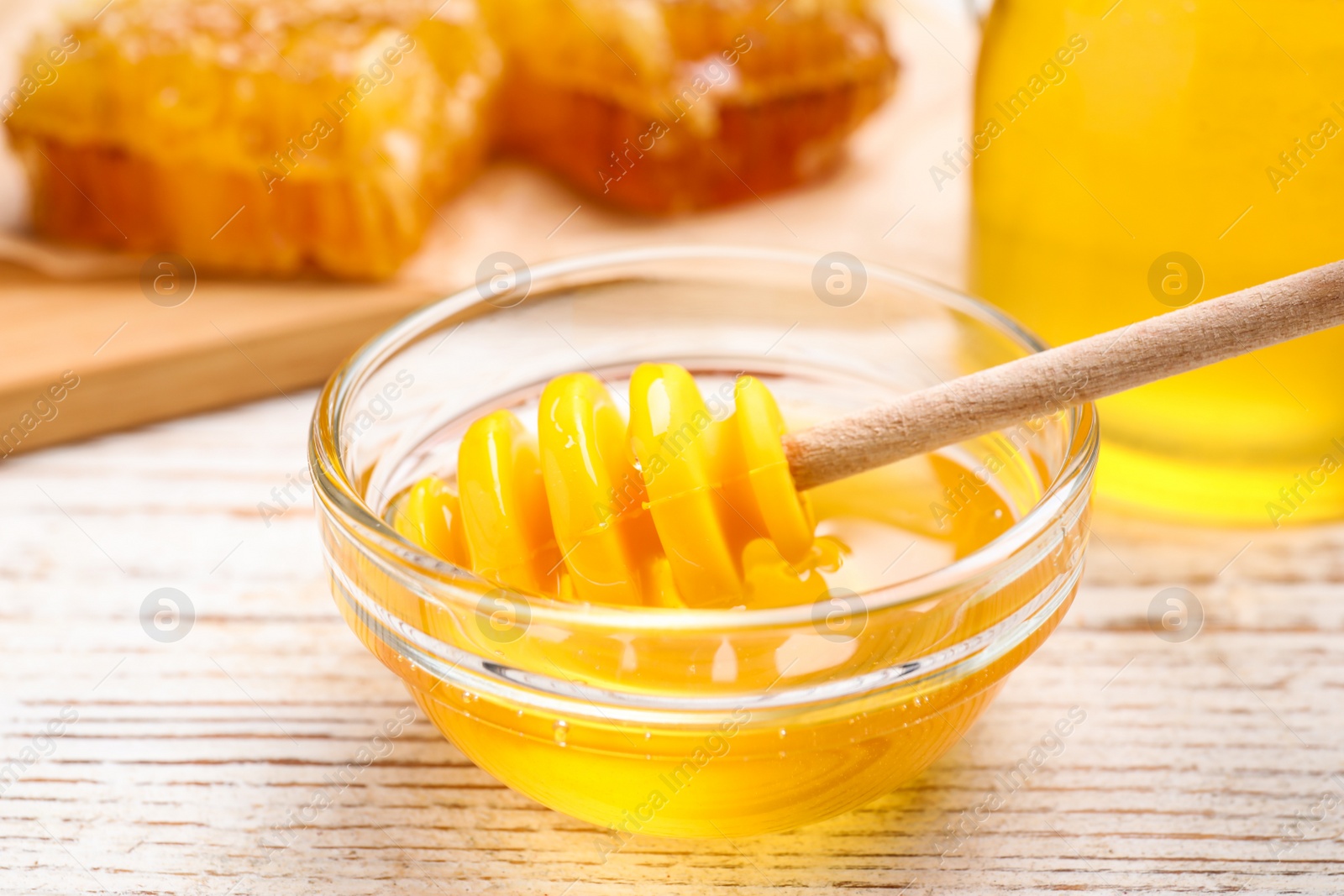 Photo of Tasty aromatic honey on white wooden table, closeup