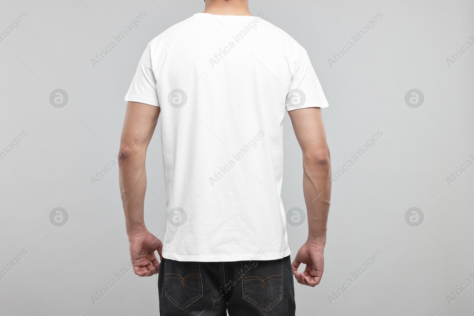 Photo of Man in white t-shirt on grey background, back view