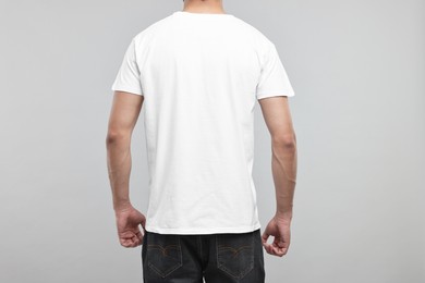 Man in white t-shirt on grey background, back view