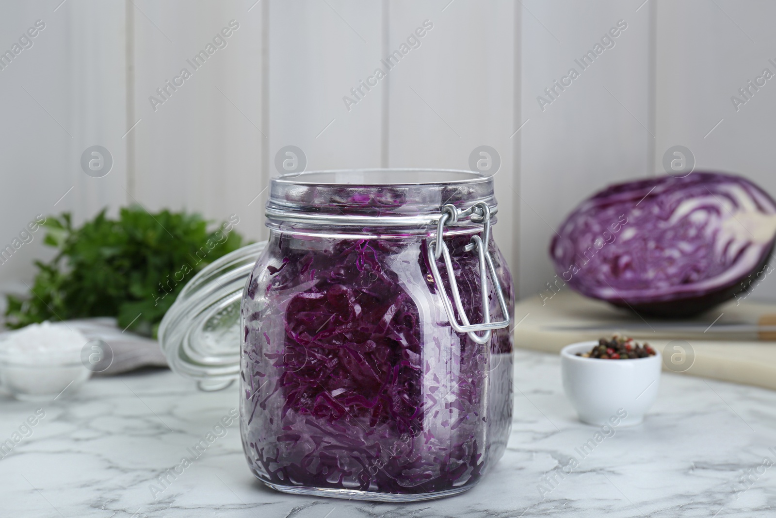 Photo of Tasty red cabbage sauerkraut and ingredients on white marble table