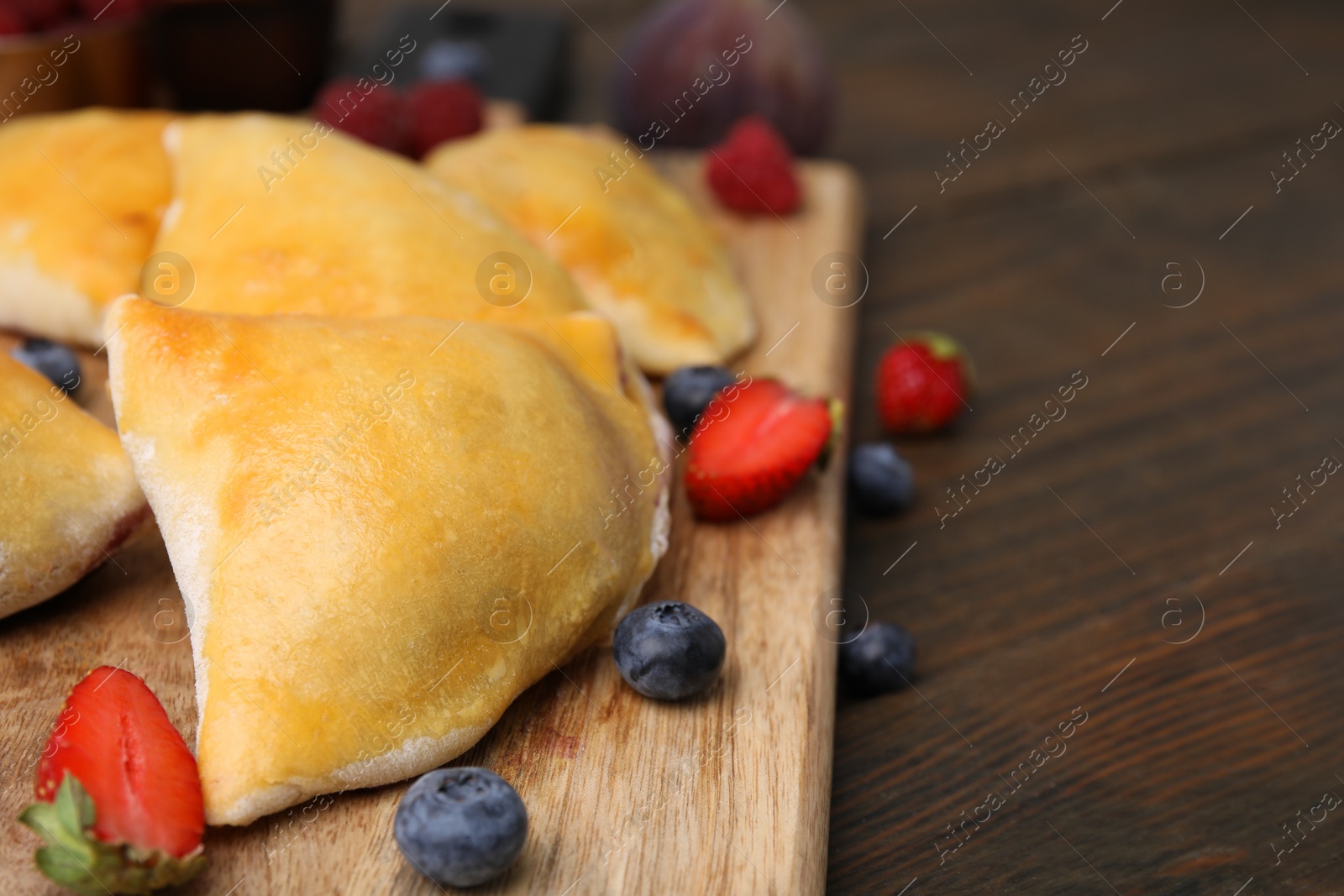 Photo of Board of delicious samosas and berries on wooden table, closeup. Space for text