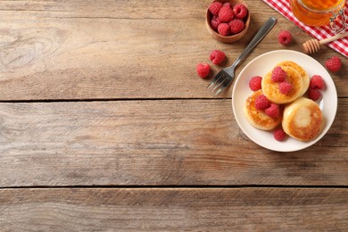 Photo of Delicious cottage cheese pancakes with raspberries on wooden table, flat lay. Space for text