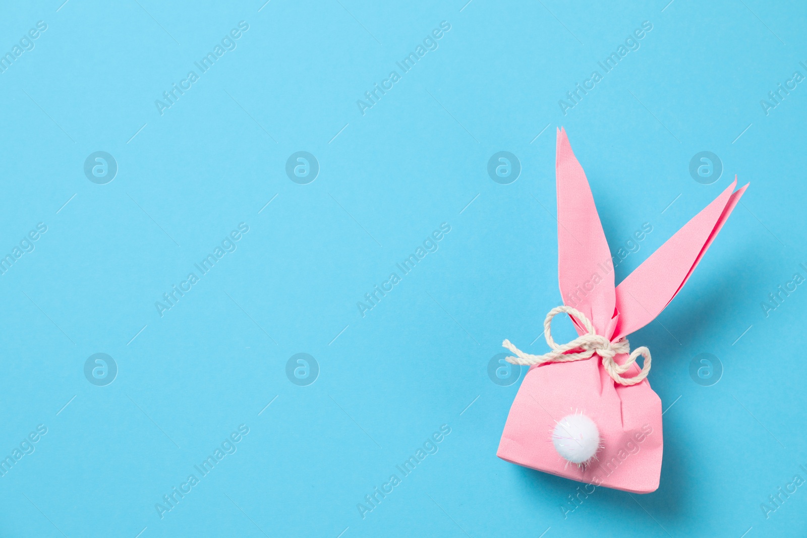 Photo of Creative Easter bunny gift bag on color background, top view with space for text