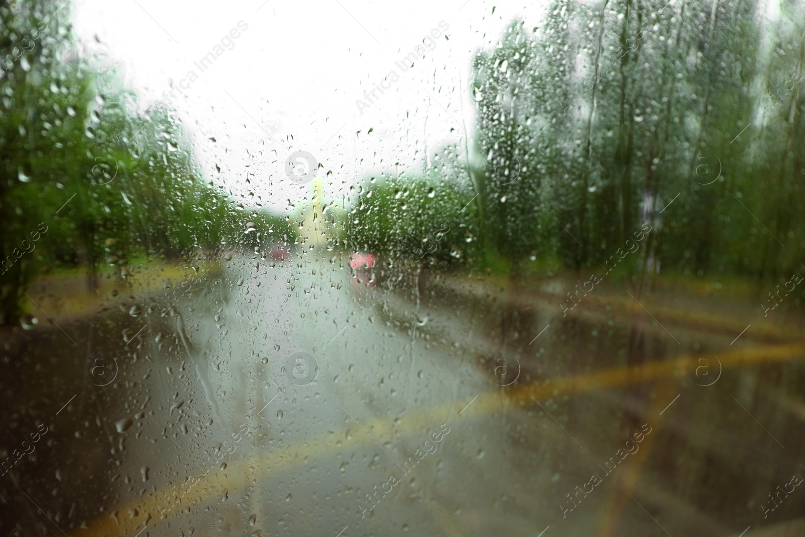 Photo of Blurred view of city street through wet window on rainy day