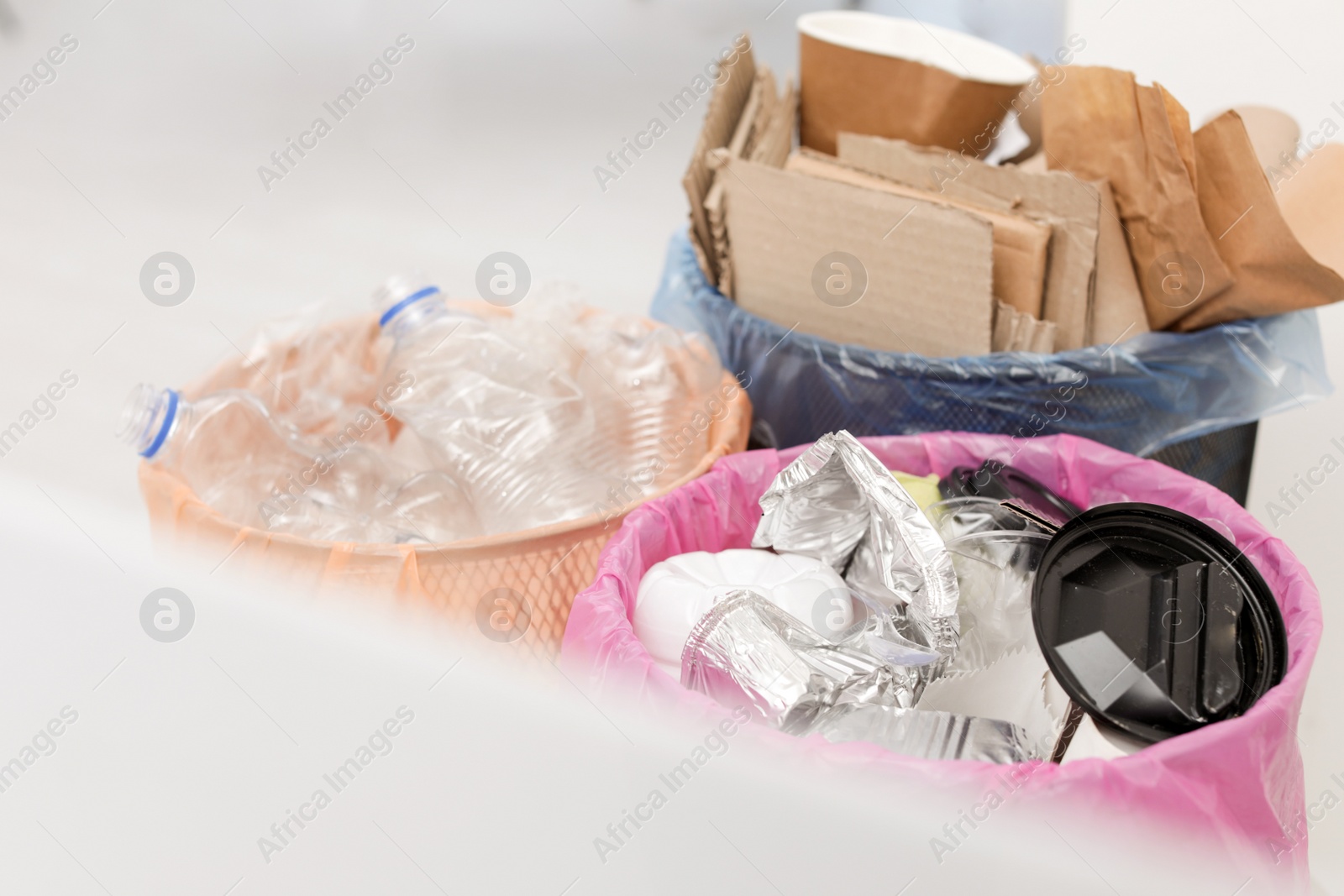 Photo of Trash cans full of garbage indoors, closeup. Waste recycling