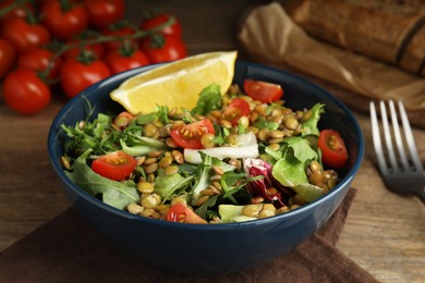 Photo of Delicious salad with lentils and vegetables on wooden table