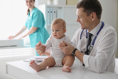 Photo of Pediatrician examining cute little baby in clinic