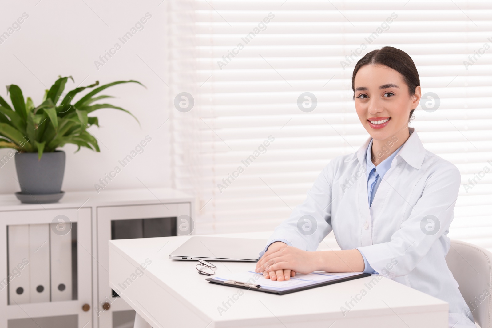 Photo of Medical consultant at table in clinic, space for text