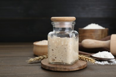 Leaven, flour and ears of wheat on wooden table