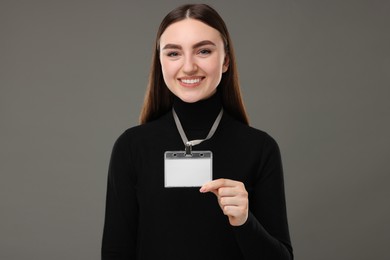 Happy woman with blank badge on grey background