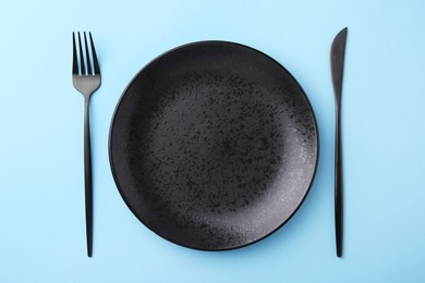 Stylish setting with elegant cutlery on light blue table, top view