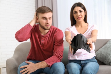 Photo of Unhappy young couple with empty wallet at home. Money problems