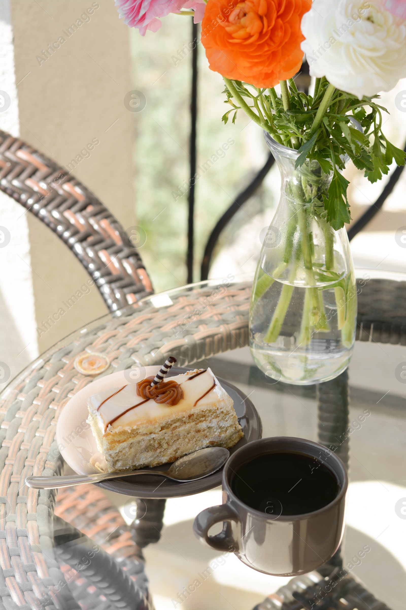 Photo of Tasty dessert, cup of fresh aromatic coffee and flowers on glass table outdoors