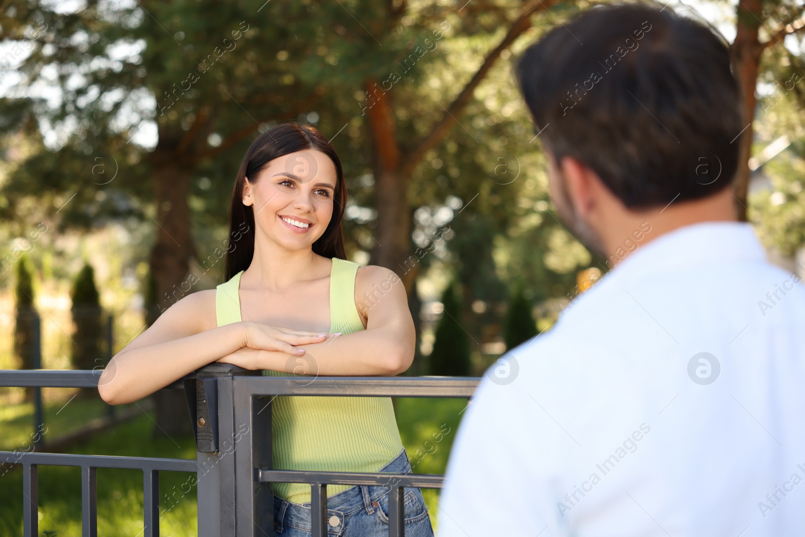 Photo of Friendly relationship with neighbours. Happy woman and man near fence outdoors