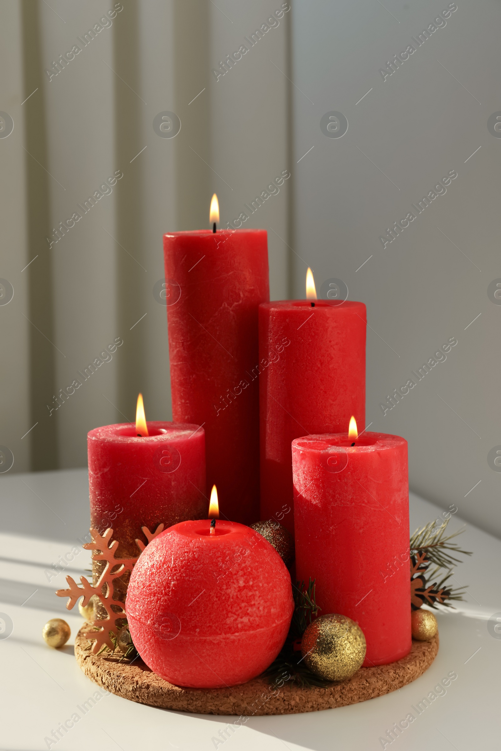 Photo of Burning candles with Christmas decor on white table