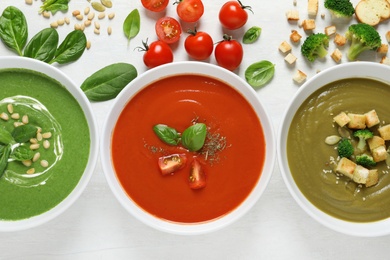 Flat lay composition with various soups and ingredients on white background. Healthy food