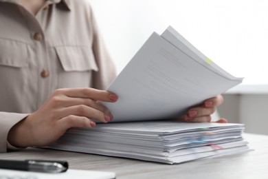 Photo of Woman reading documents at wooden table in office, closeup