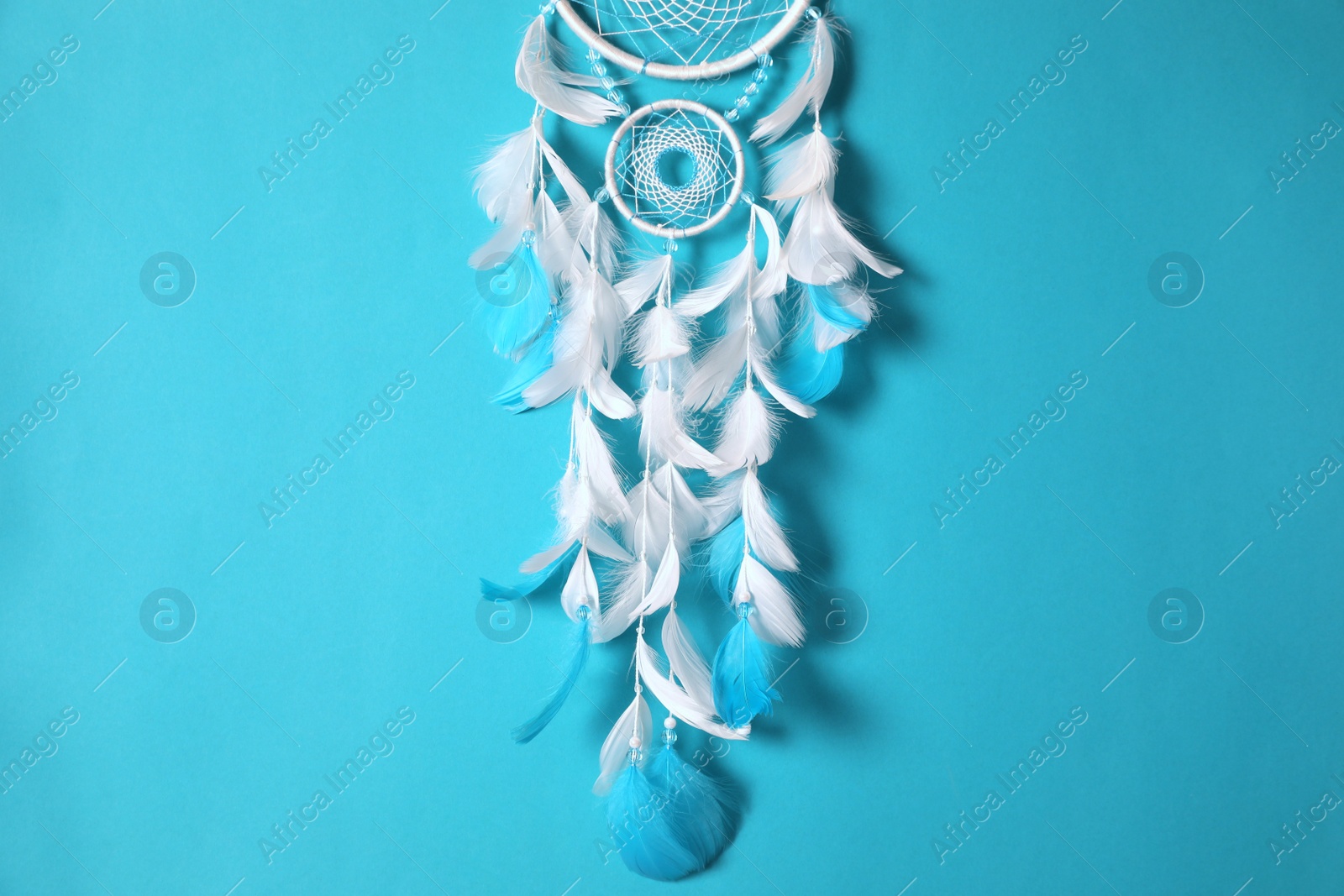 Photo of Beautiful dream catcher hanging on light blue background