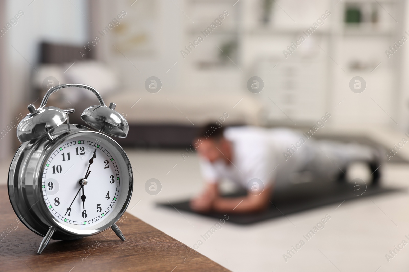 Photo of Man doing morning exercise on fitness mat at home, selective focus. Space for text