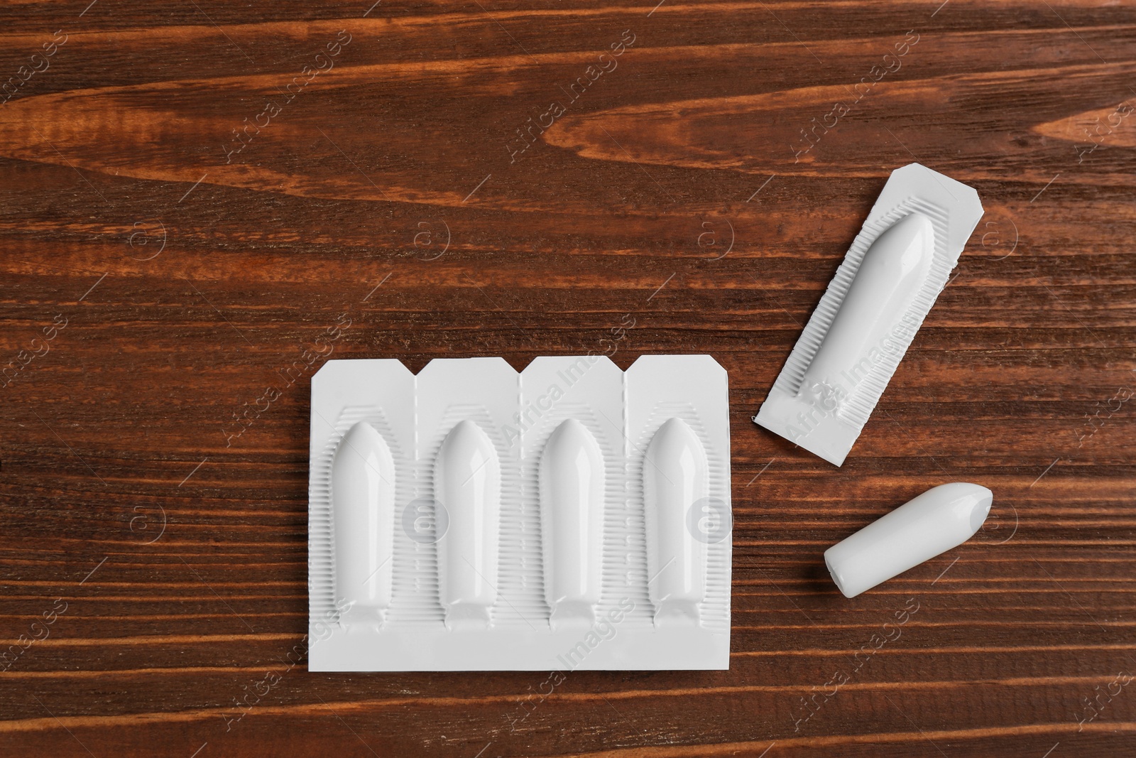 Photo of Suppositories on wooden background, flat lay. Hemorrhoid treatment