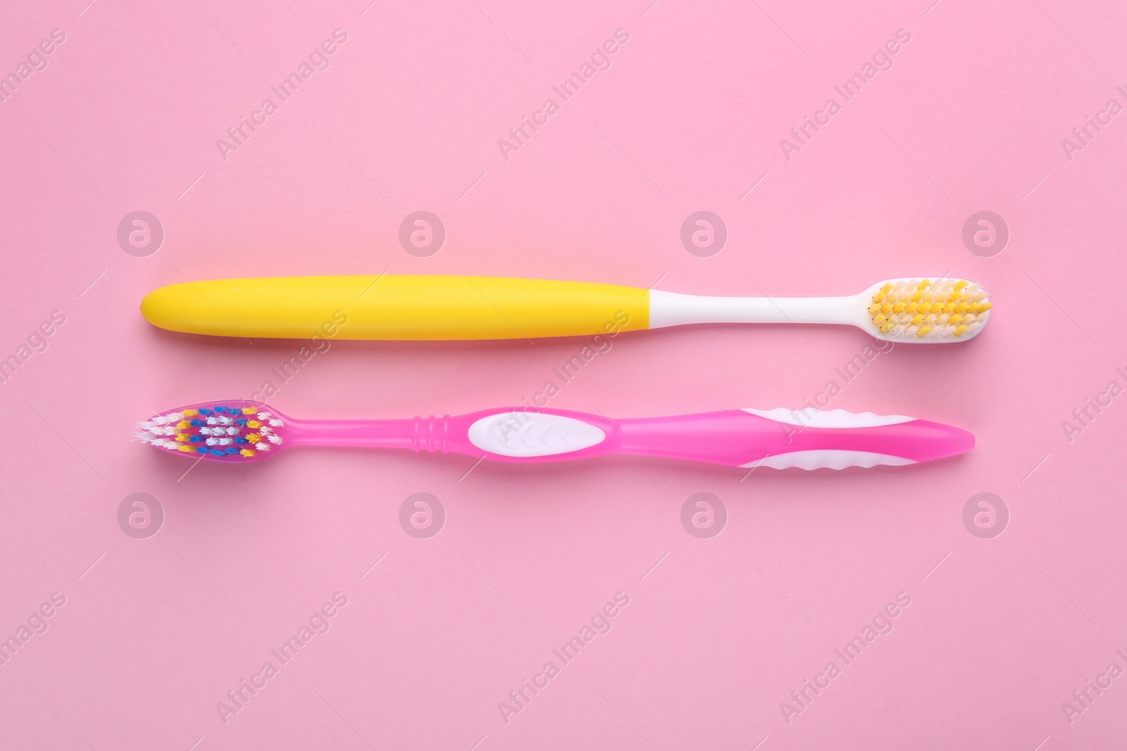 Photo of Two toothbrushes on pink background, flat lay