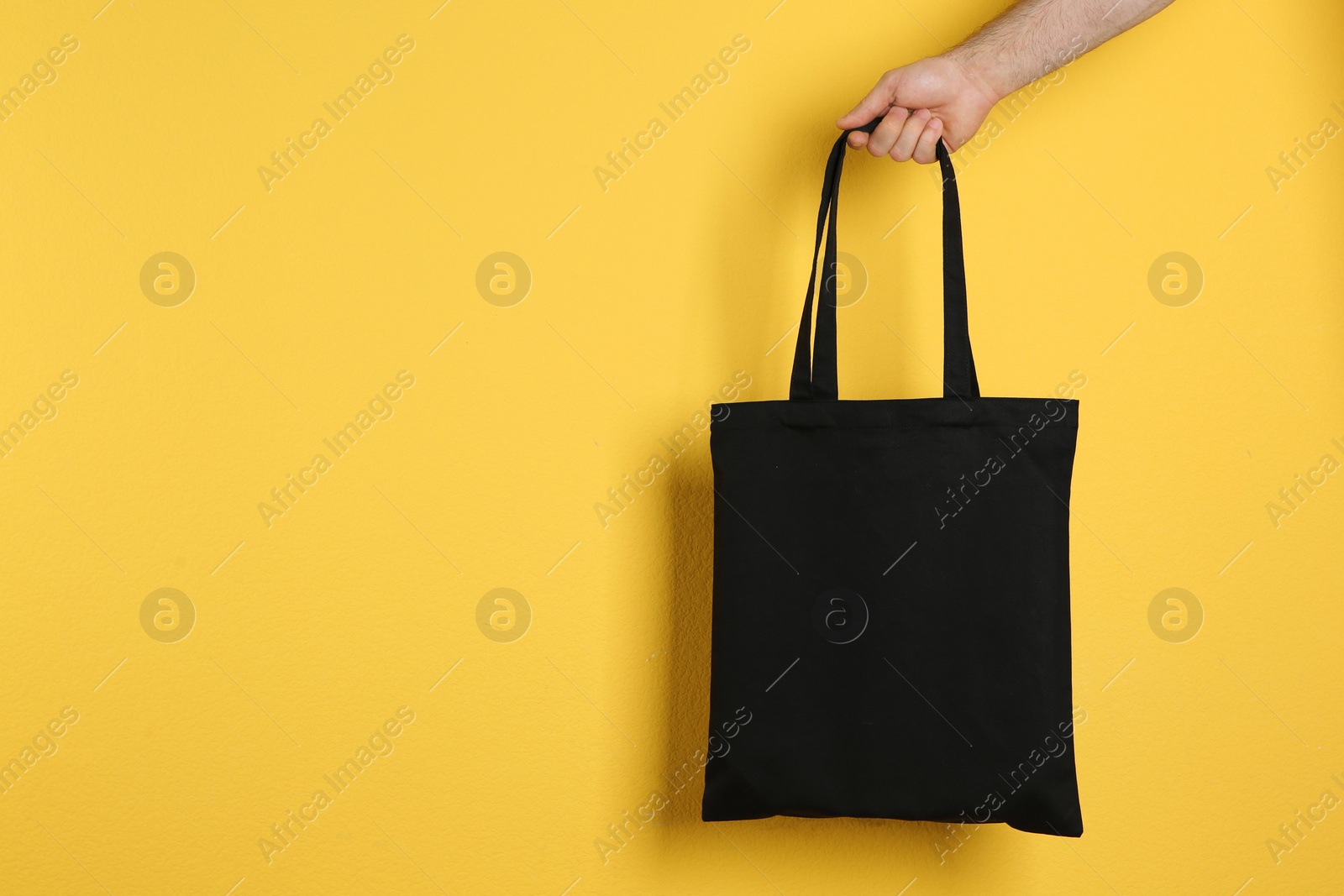 Photo of Man holding cotton shopping eco bag on color background. Mockup for design