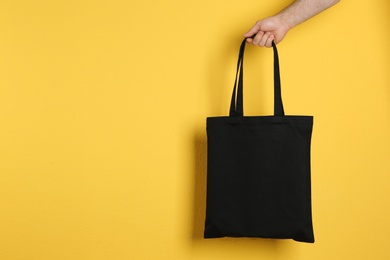 Photo of Man holding cotton shopping eco bag on color background. Mockup for design