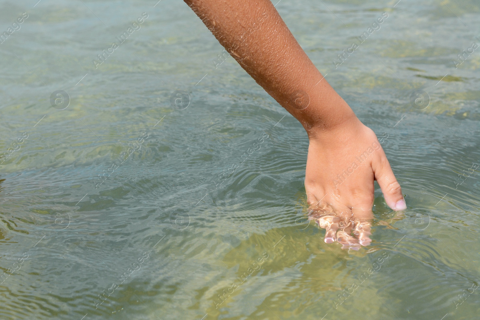 Photo of Kid touching cool clear water outdoors, closeup