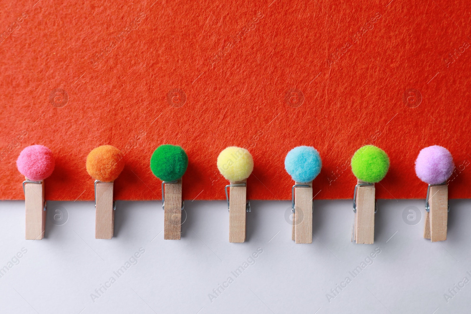 Photo of Sheet of red felt with clothespins and small soft balls on white background, top view