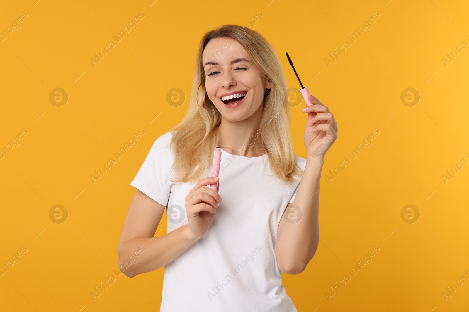 Photo of Beautiful woman with mascara on orange background