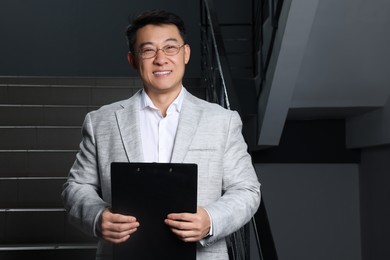Photo of Happy boss with clipboard in his office