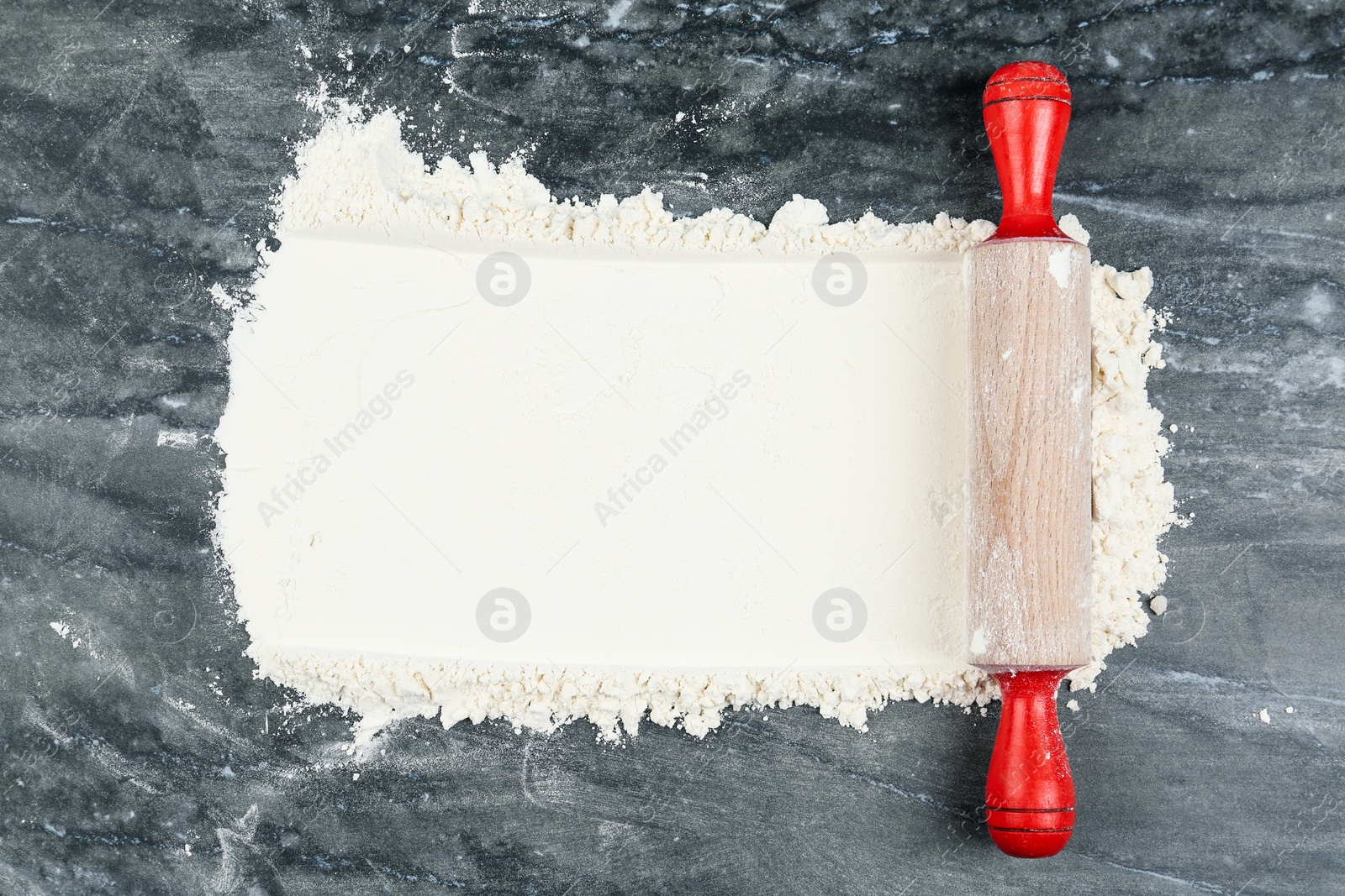 Photo of Flour and rolling pin on grey marble table, top view. Space for text