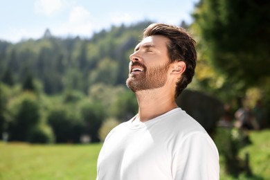 Photo of Feeling freedom. Man enjoying nature outdoors on sunny day, space for text