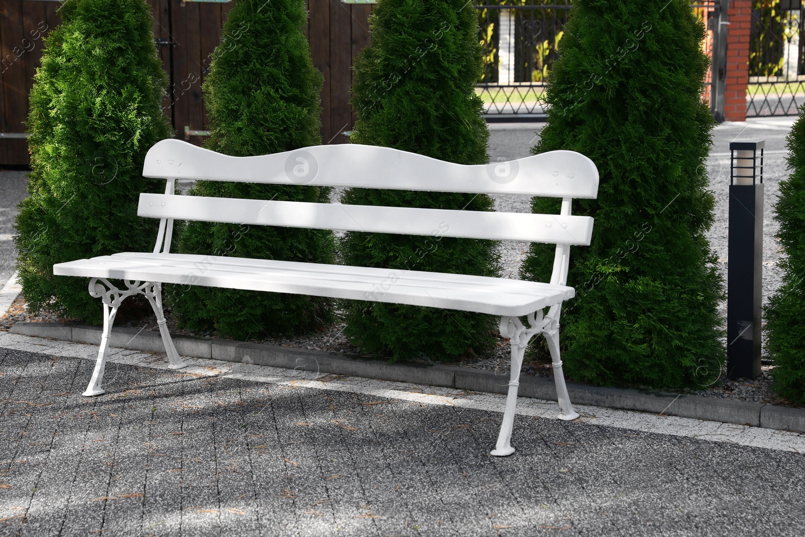 Photo of Stylish white wooden bench in garden on sunny day