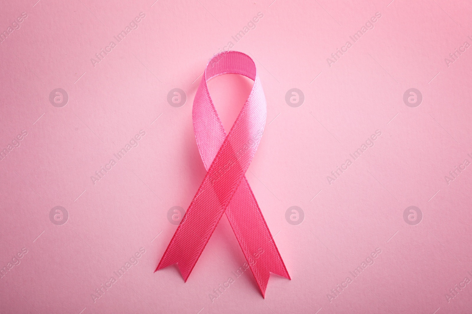 Photo of Pink ribbon on color background, top view. Breast cancer awareness concept