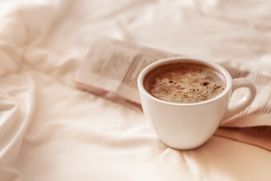 Photo of Morning coffee and newspaper on bed. Space for text