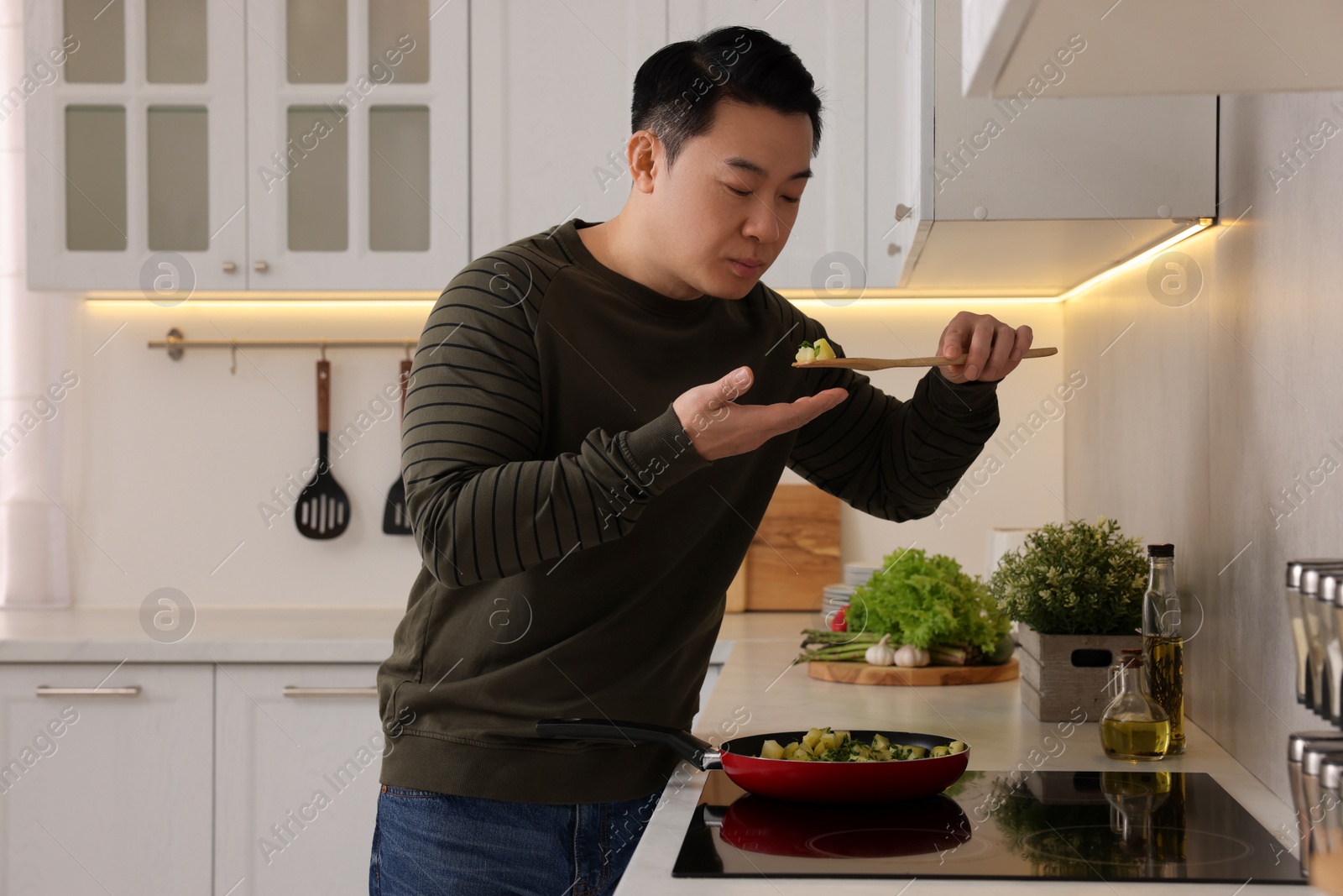 Photo of Cooking process. Man tasting potato in kitchen, space for text