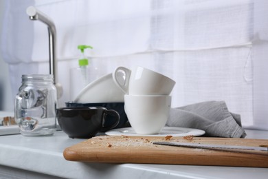 Many dirty utensils and dishware on countertop in messy kitchen