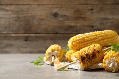 Delicious grilled corn cobs on grey table. Space for text