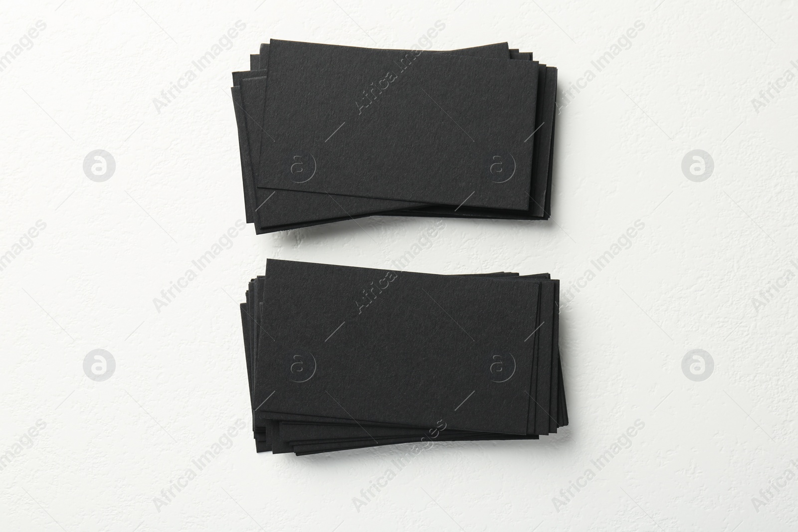 Photo of Blank black business cards on white table, top view