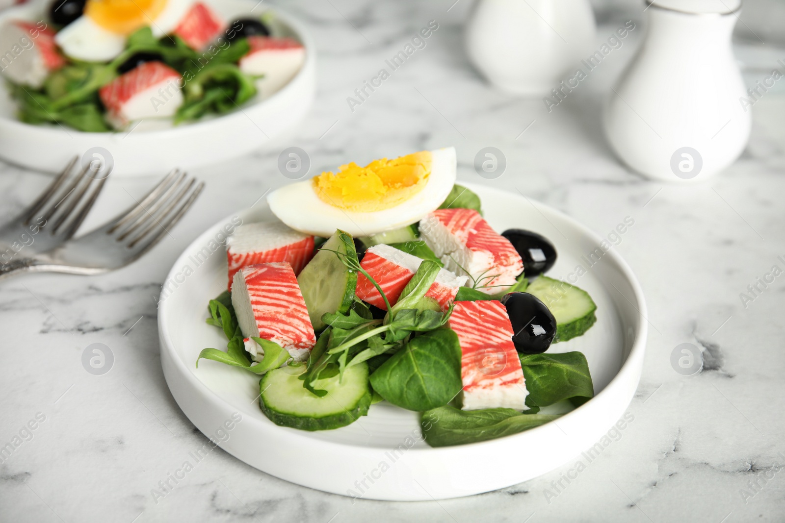 Photo of Delicious crab stick salad served on white marble table