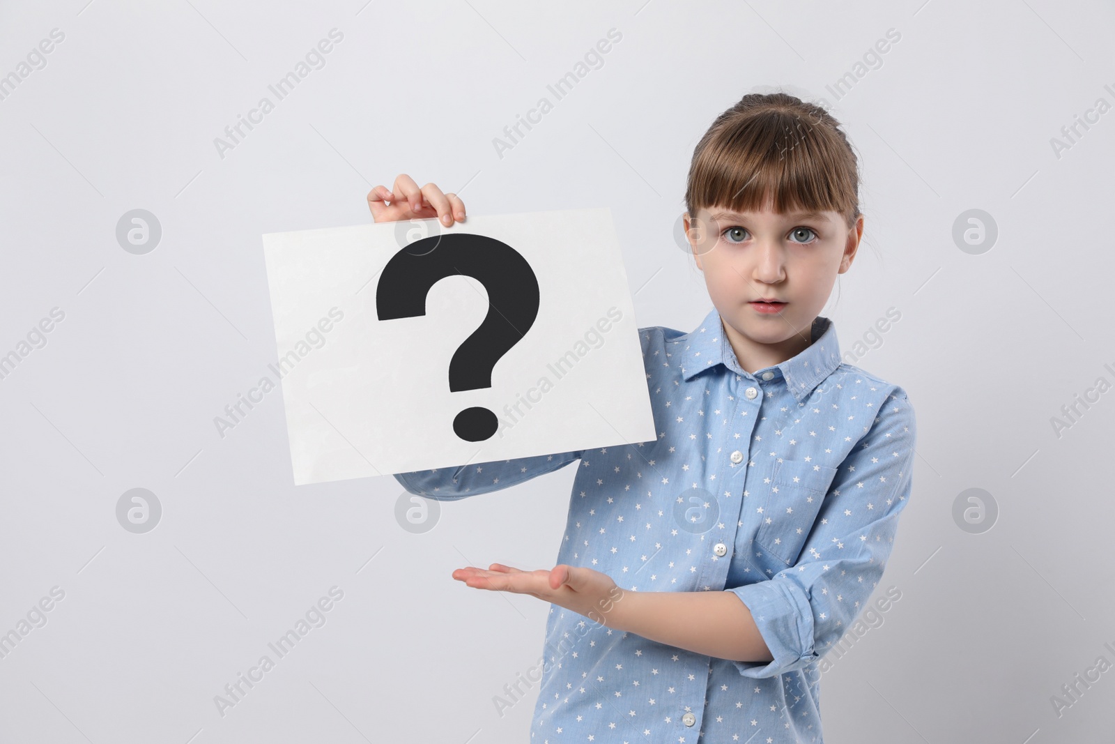 Photo of Emotional girl holding sheet of paper with question mark on white background