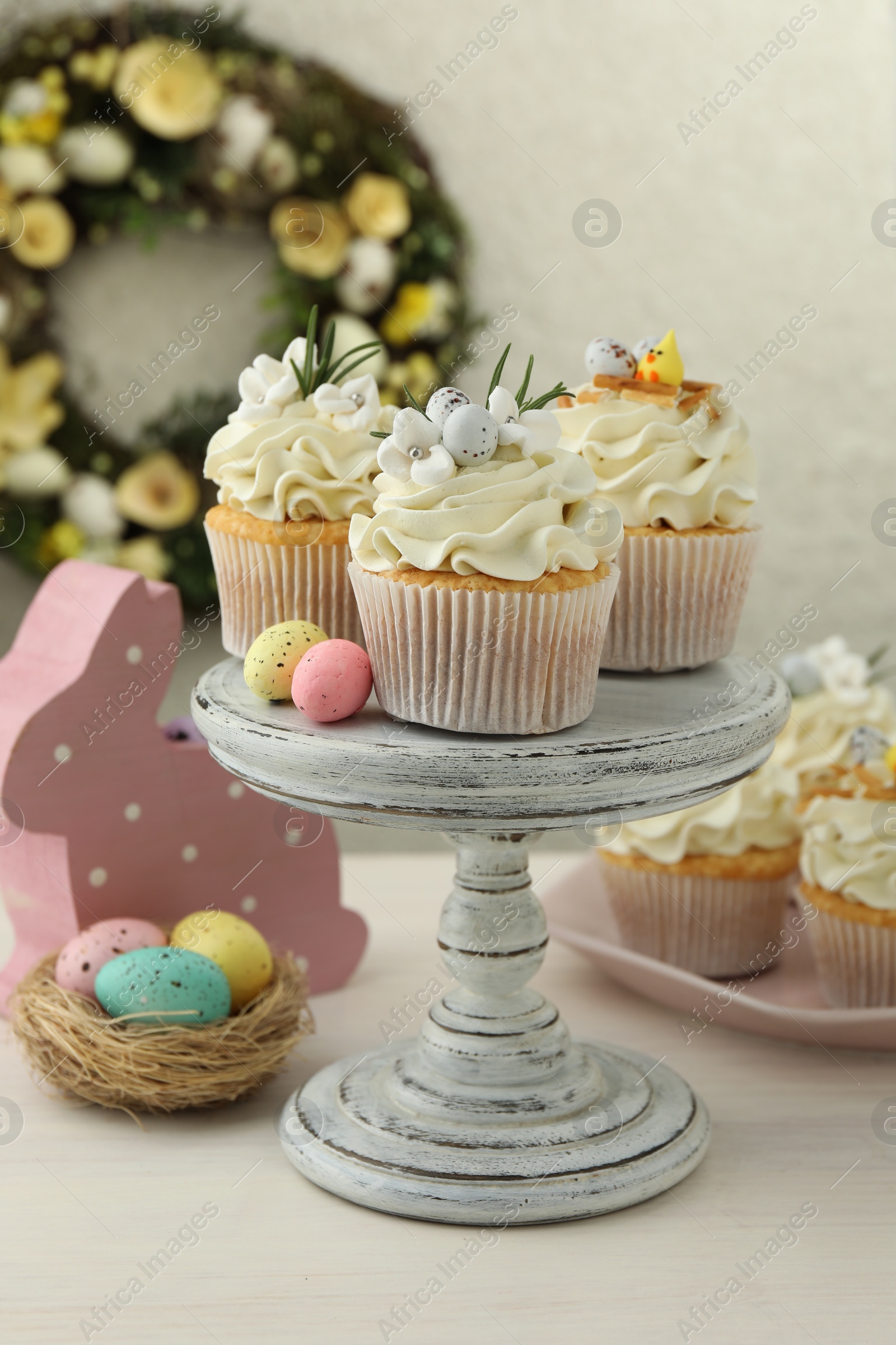 Photo of Tasty Easter cupcakes with vanilla cream and festive decor on light wooden table