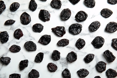 Photo of Flat lay of dried plums on marble background. Healthy fruit