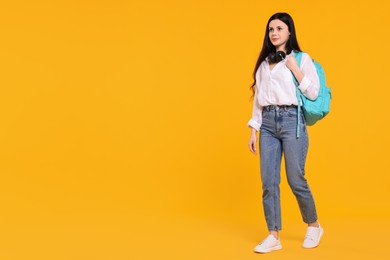 Student with backpack and headphones on yellow background. Space for text