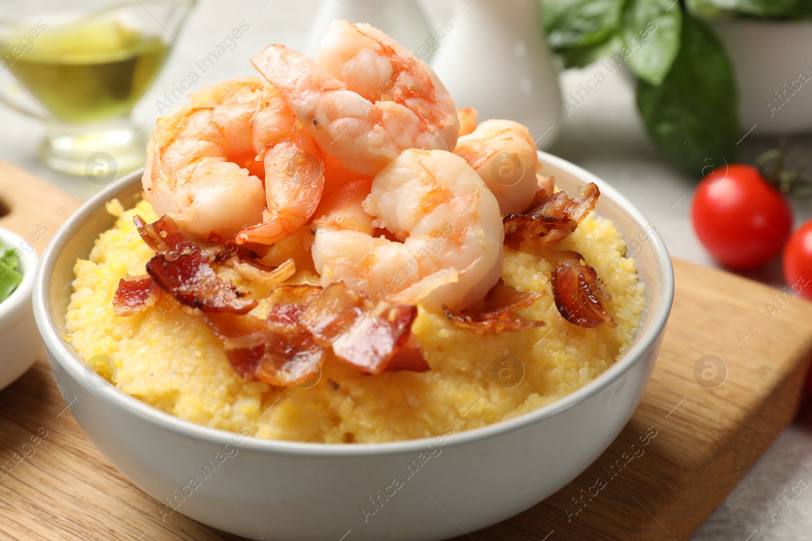 Photo of Fresh tasty shrimps, bacon and grits in bowl on table, closeup