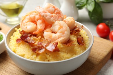 Photo of Fresh tasty shrimps, bacon and grits in bowl on table, closeup