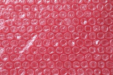 Transparent bubble wrap on red background, top view