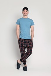 Happy man in pyjama and sleep mask on light grey background